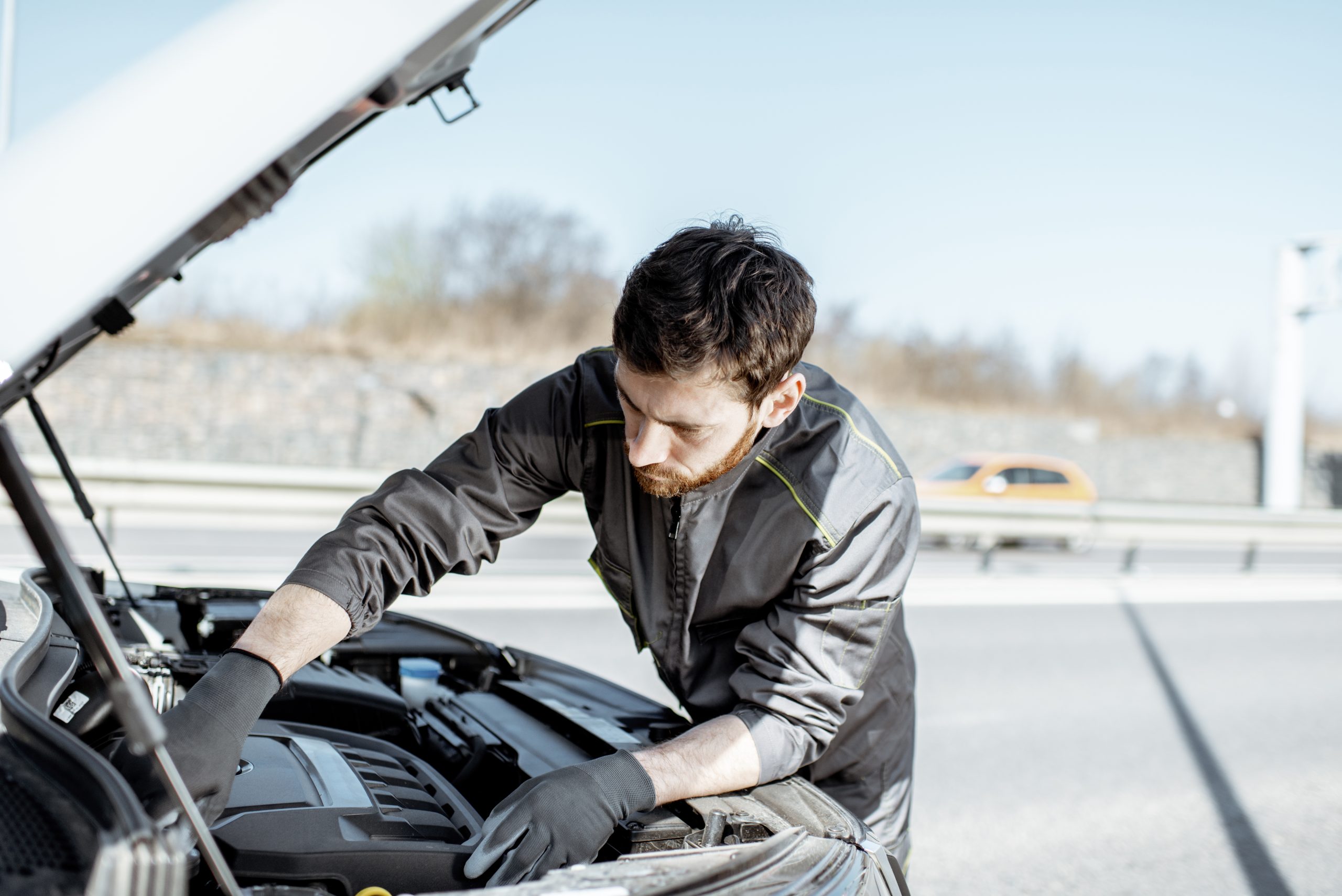 Técnico inspeccionando el motor de un auto al aire libre